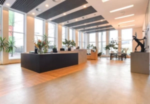 Moderne en lichte ontvangsthal aan de Barbara Strozzilaan met een receptiebalie, grote ramen en stijlvolle inrichting.